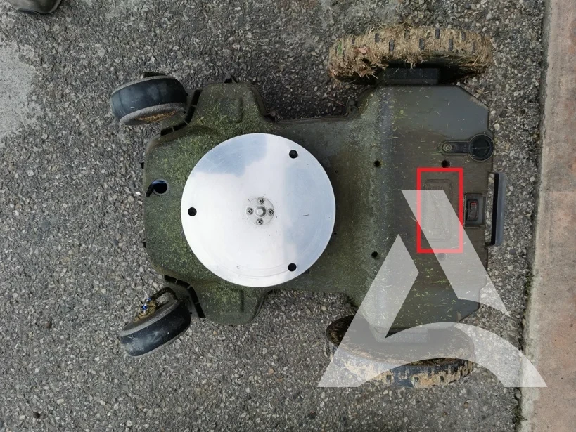 Dessous de robot tondeuse encrassé par l’herbe et les résidus végétaux