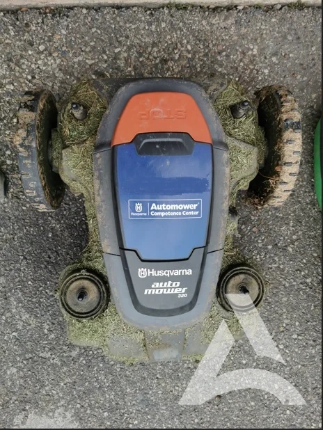 Robot tondeuse encrassé par l’herbe et la boue avant nettoyage